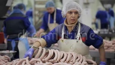 肉类产品制造。 生产部门。 员工整理香肠的末端。 工人在线香肠上